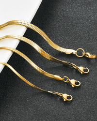 Flat herringbone snake chain necklace in stainless steel with smooth, ribbon-like design, available in gold and silver, multiple widths and lengths, tarnish-resistant and waterproof.