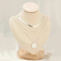 Gold layered coin disc pendant on flat snake chain necklace displayed on white background
