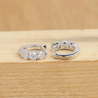 Close-up of 925 sterling silver moissanite hoop earrings with round D/VVS1 stones, showcasing luxury sparkle and classic design