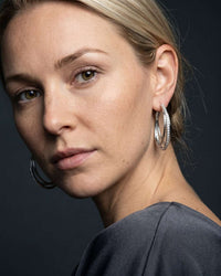Silver plated Orbit crossover hoop earrings with cubic zirconia pavé detail