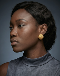 Close-up of textured dome stud earrings with 18K gold plating and woven design